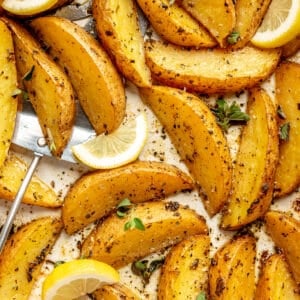 Close up of Greek-Style Potatoes with lemon wedges.