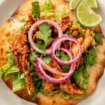 Easy Rotisserie Chicken Tostada on a white plate with lime wedge.