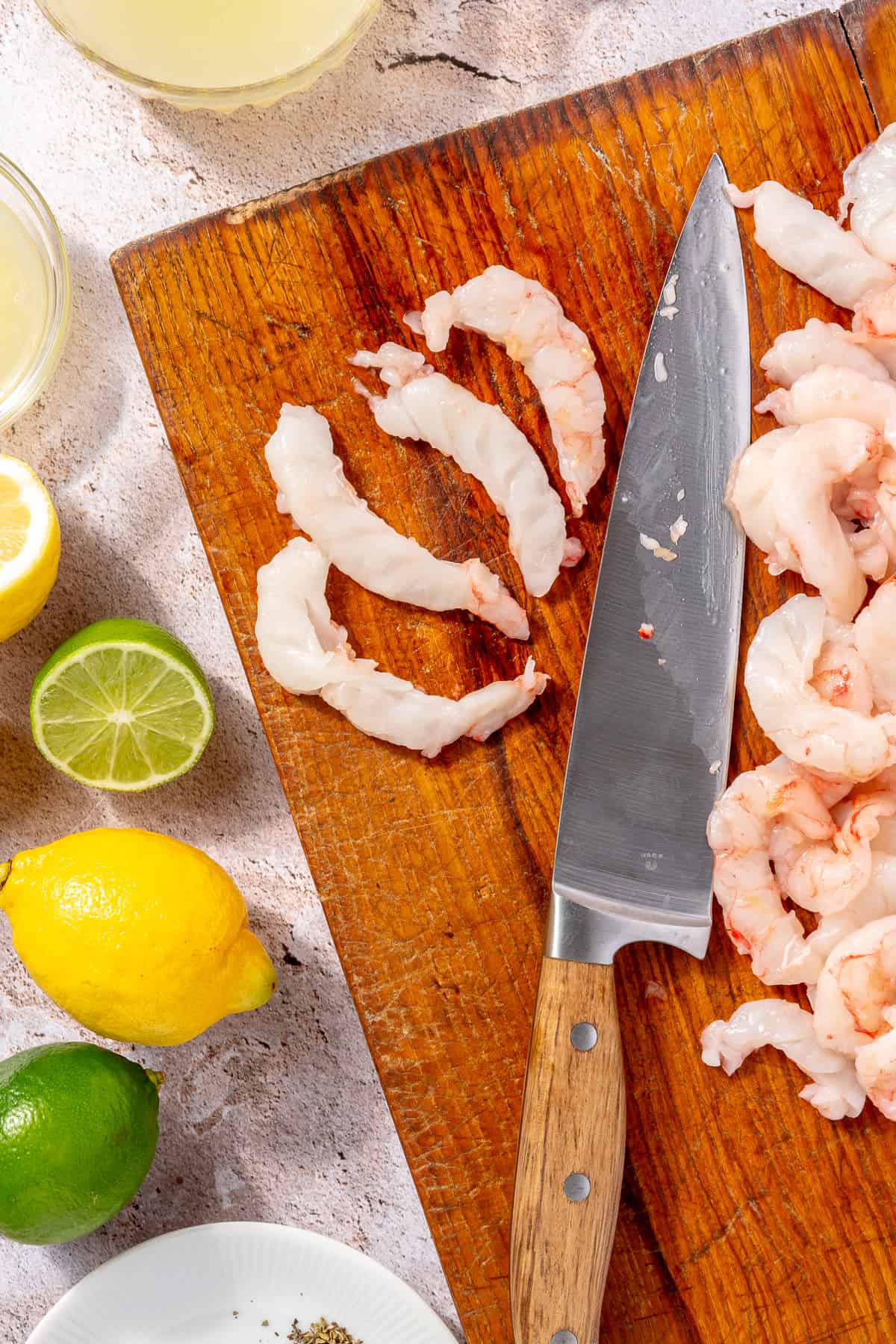 Raw shrimp on cutting board. Two pieces of shrimp sliced lenghtwise.