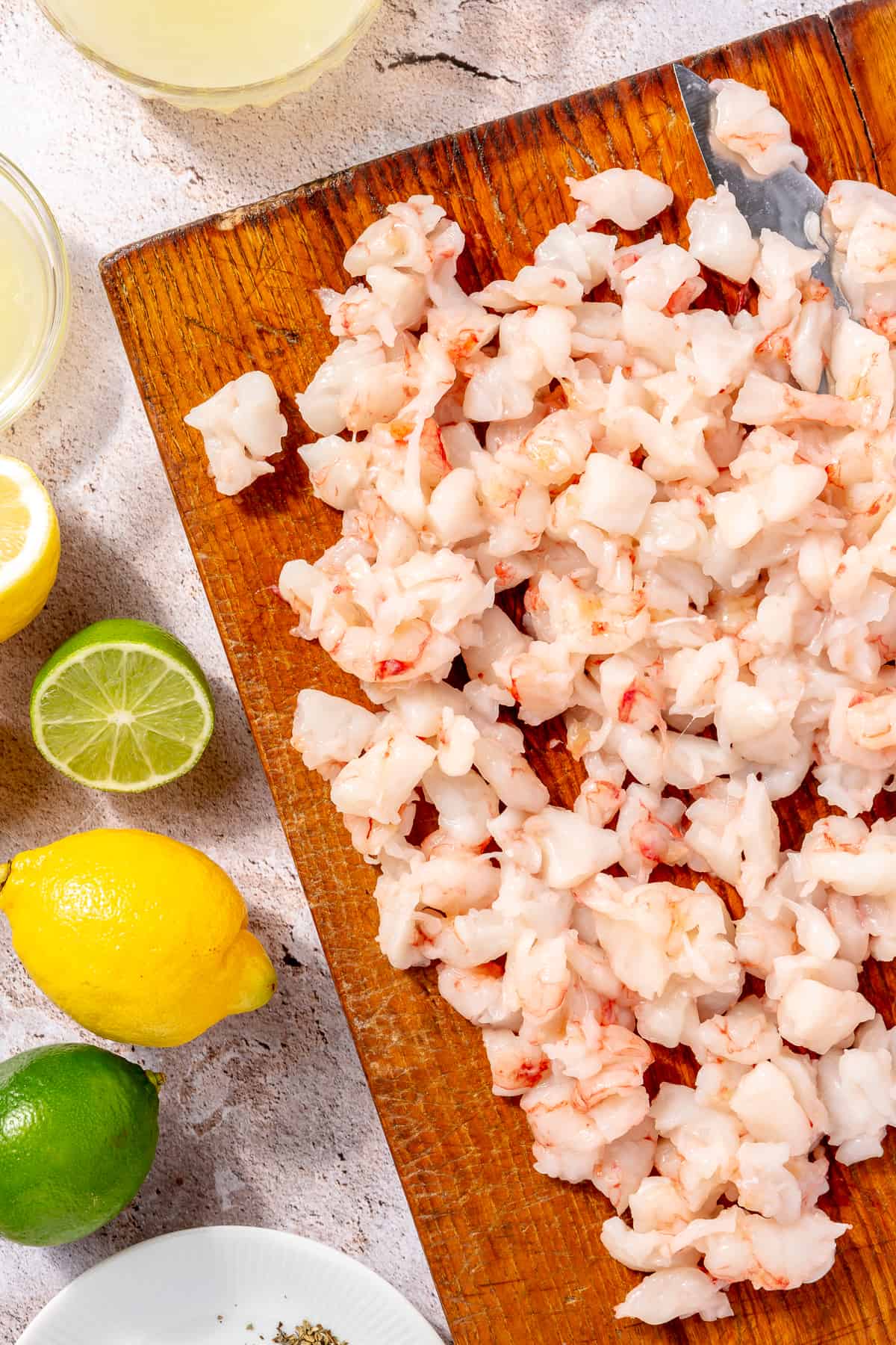 Chopped shrimp on cutting board. Lemons and limes on the side peeking in.