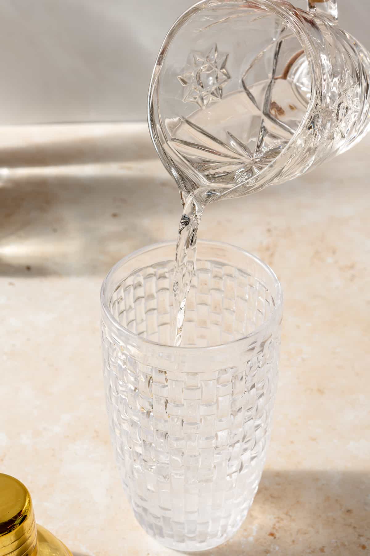 Vodka pouring into glass shaker.