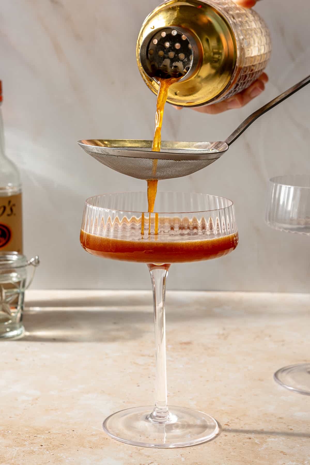 Espresso martini being strained into martini glass.