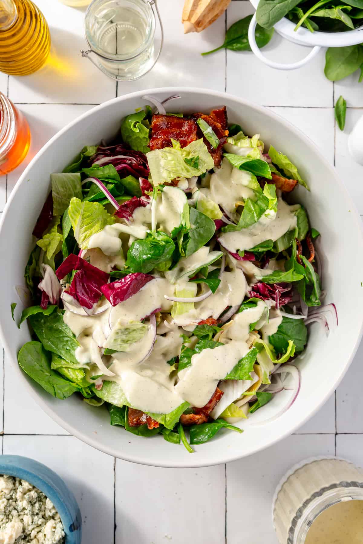 Tossed salad in large white bowl with dressing on top.