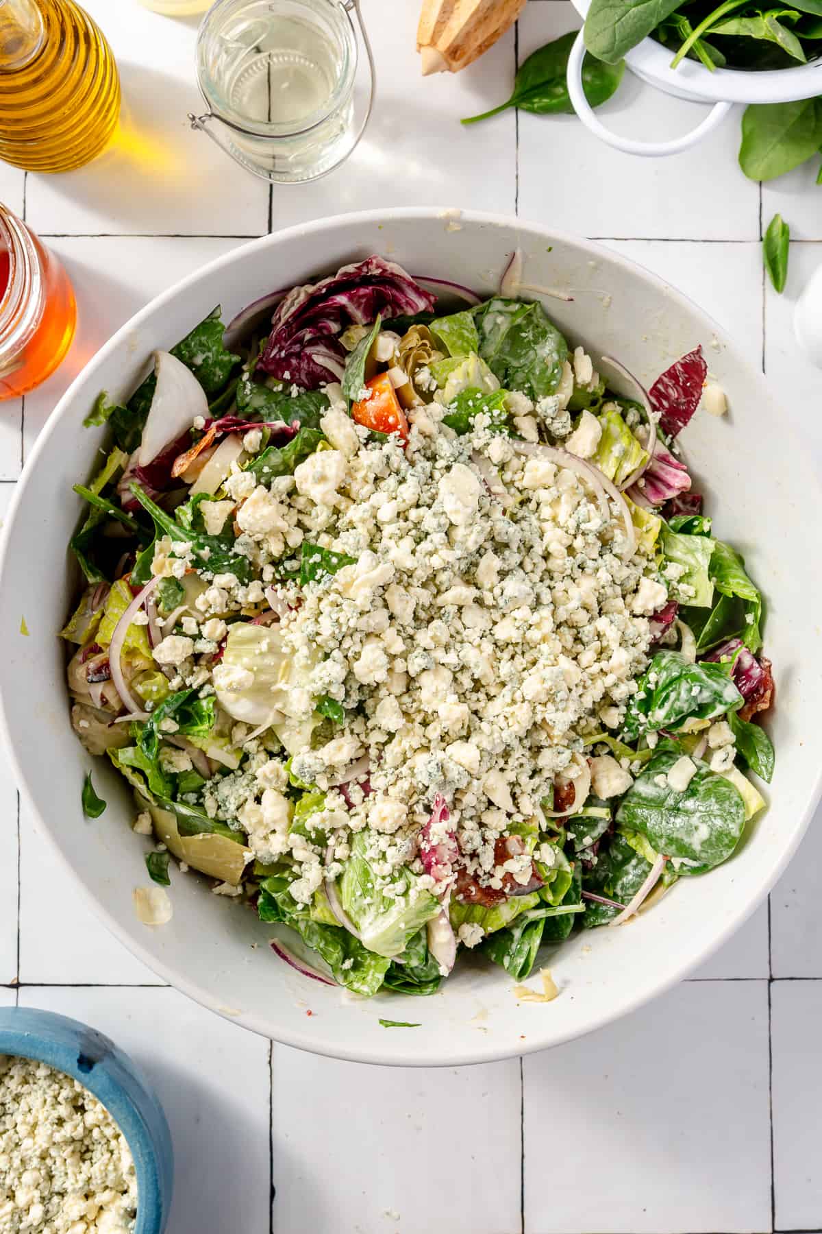 Tossed salad in large white bowl with gorgonzola on top.
