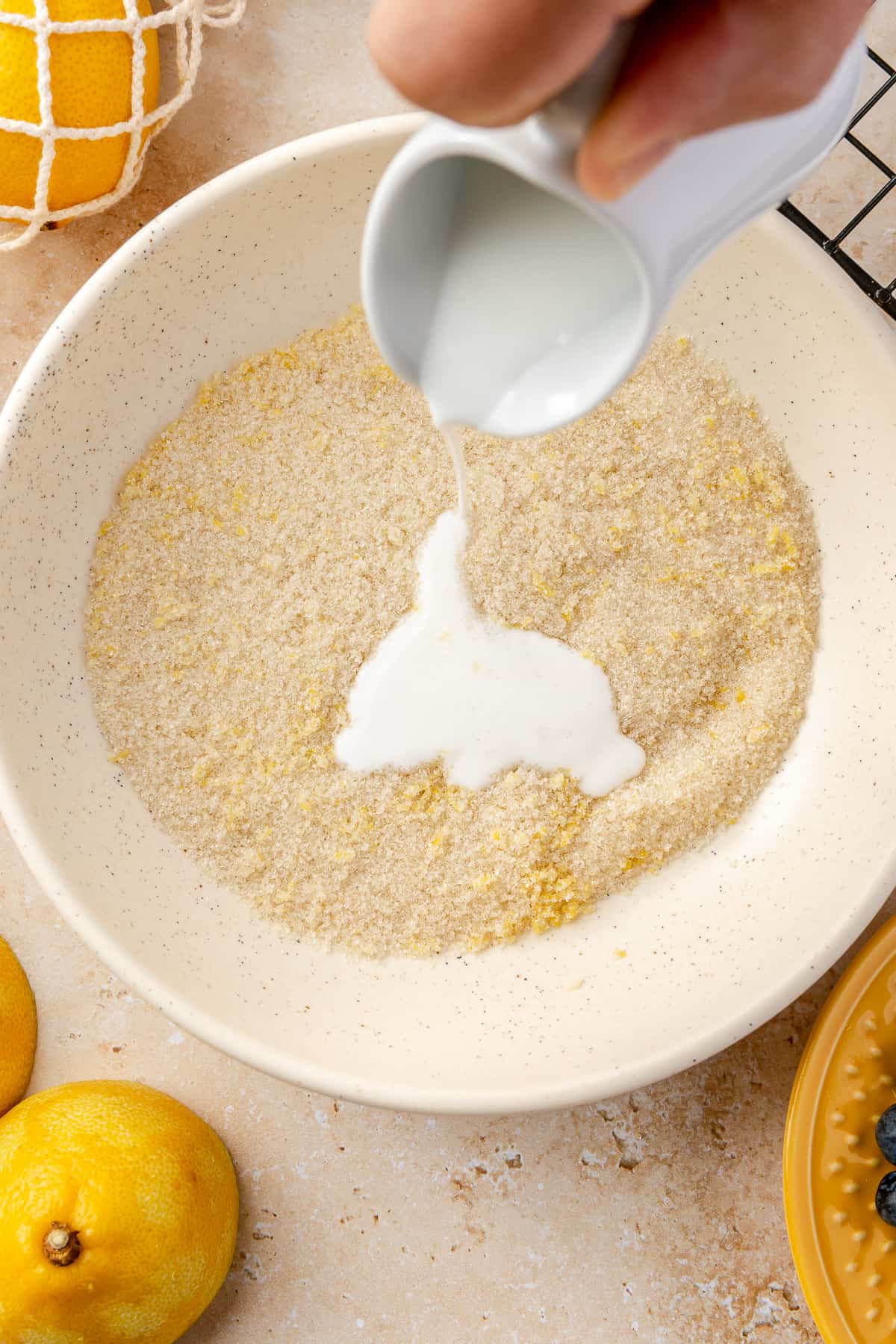 Buttermilk pouring into bowl of lemon zest and sugar mixture. 