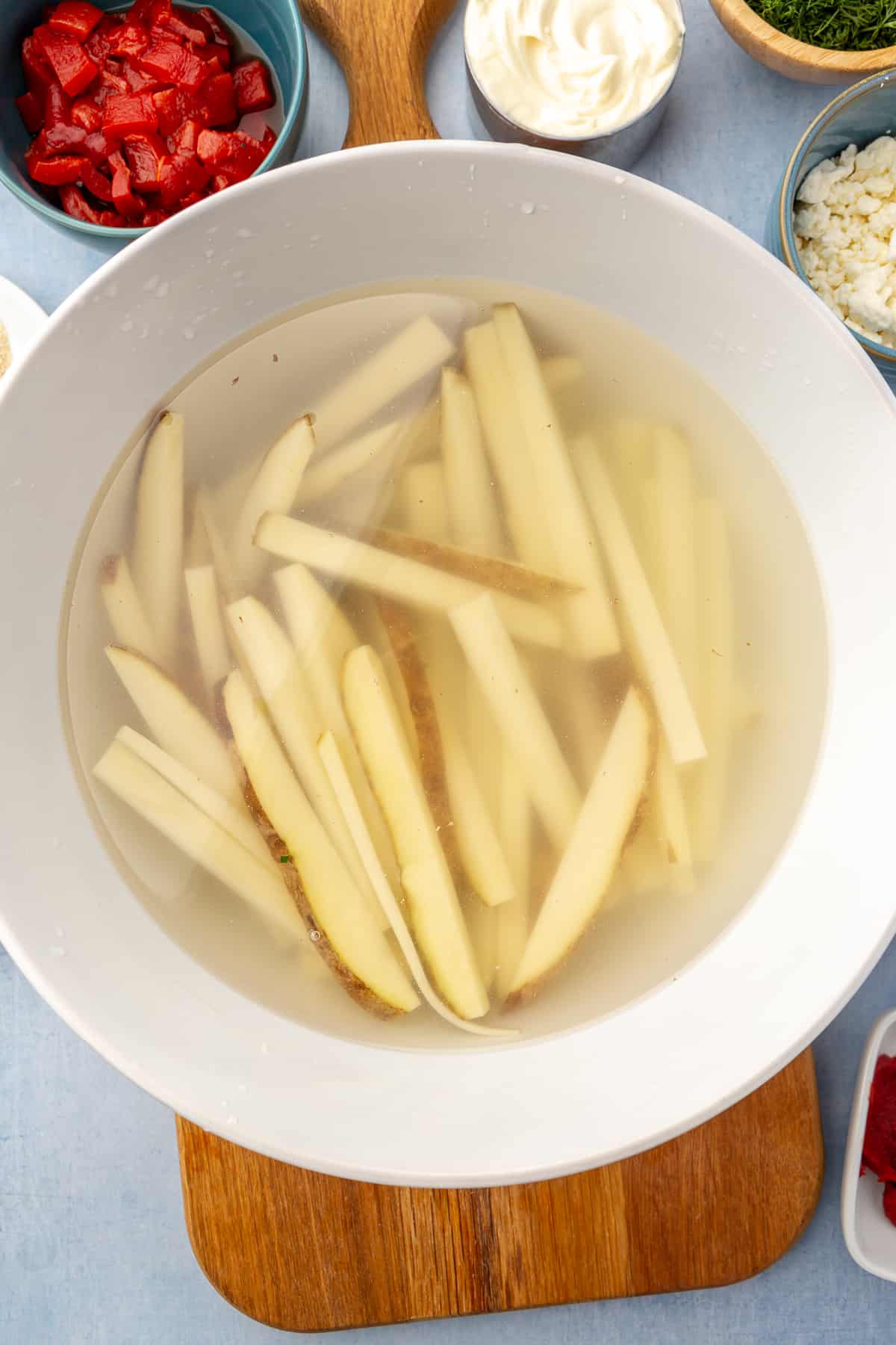 Bowl of water filled with cut potatoes.
