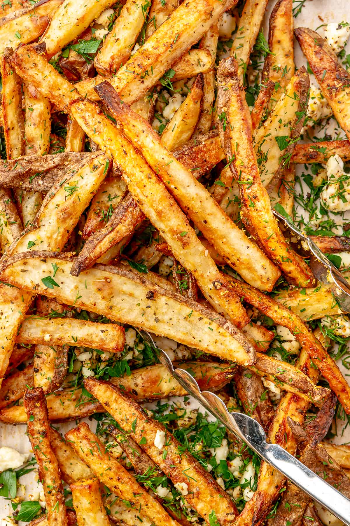Close up of fries on sheet pan with garlic and herbs.