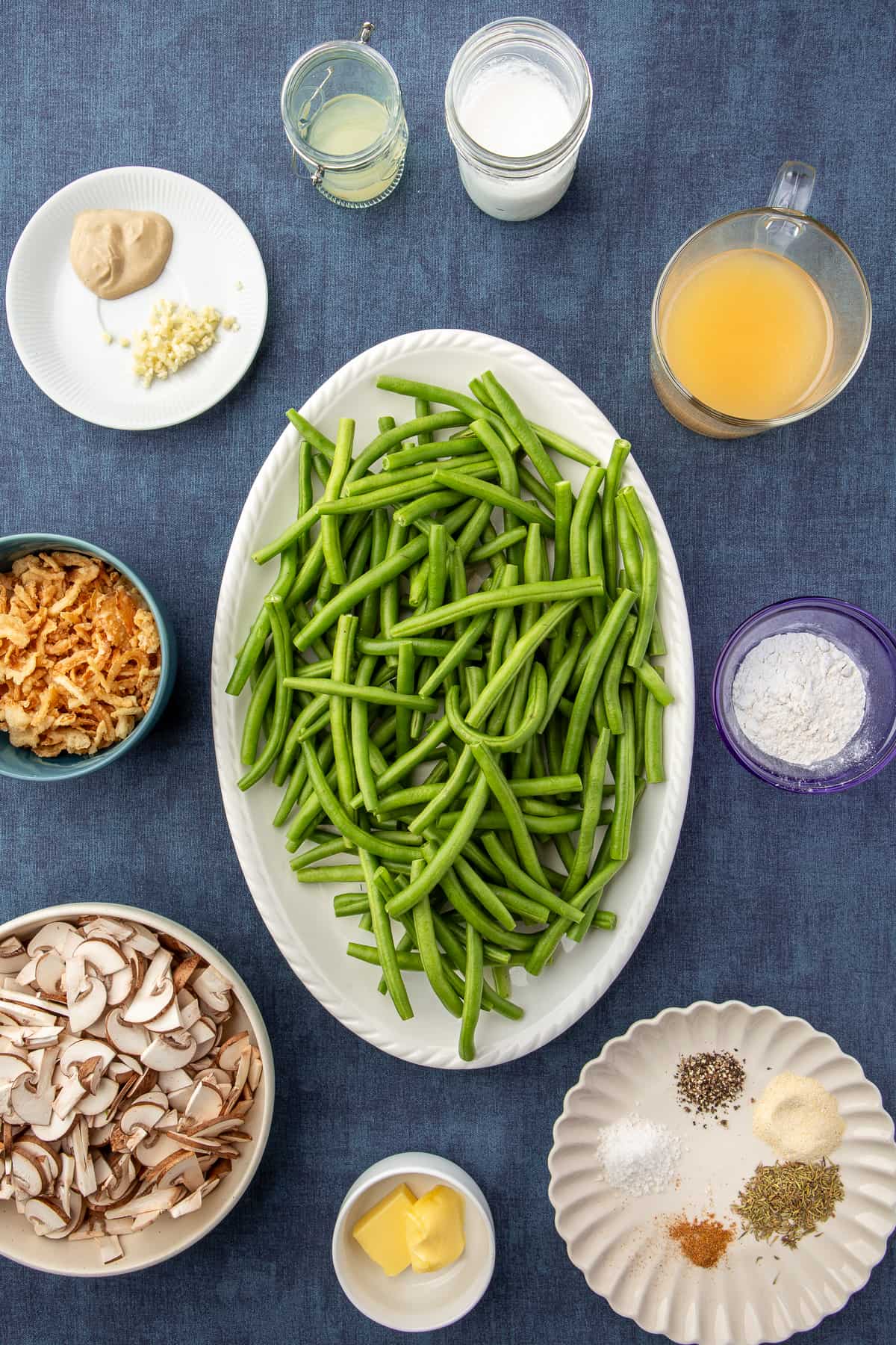 Ingredients for Homemade Green Bean Casserole scattered on dark background.
