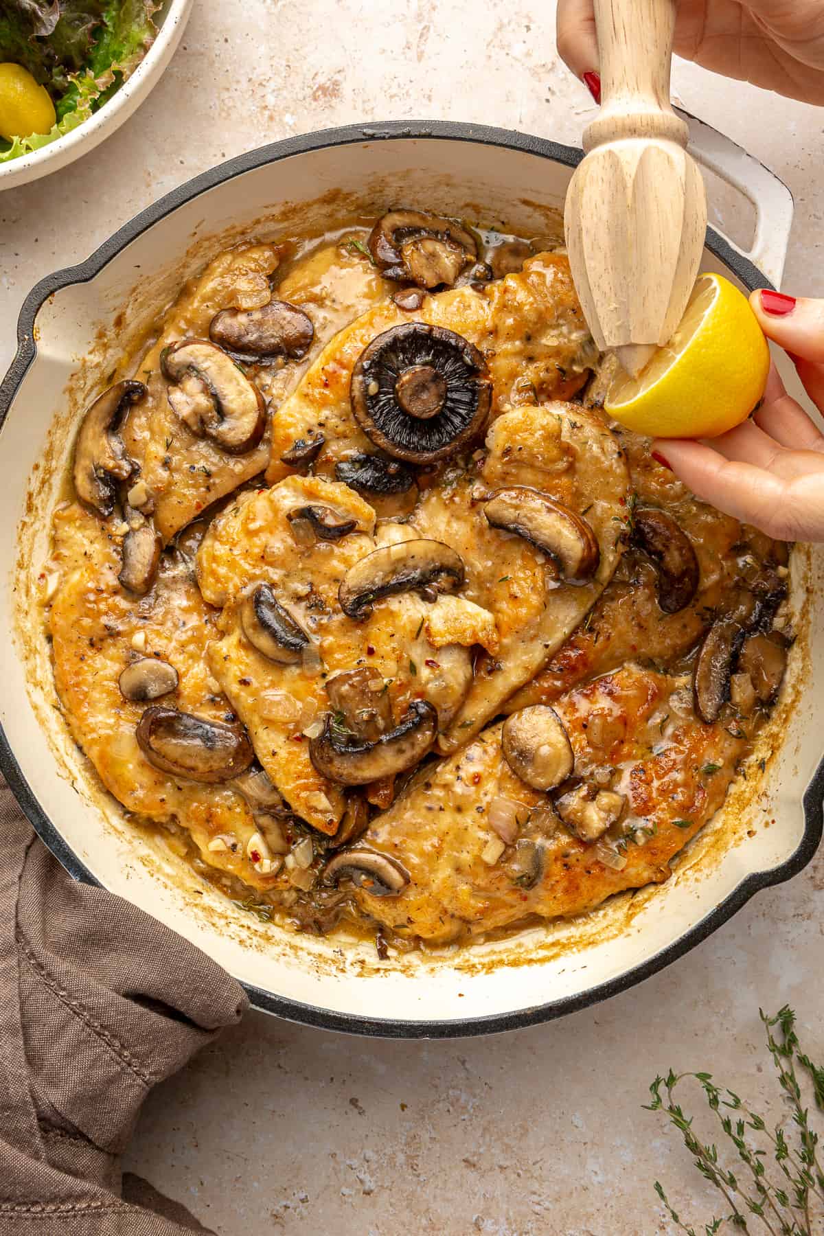 Whole30 Chicken Marsala in skillet with lemon being squeezed over it.