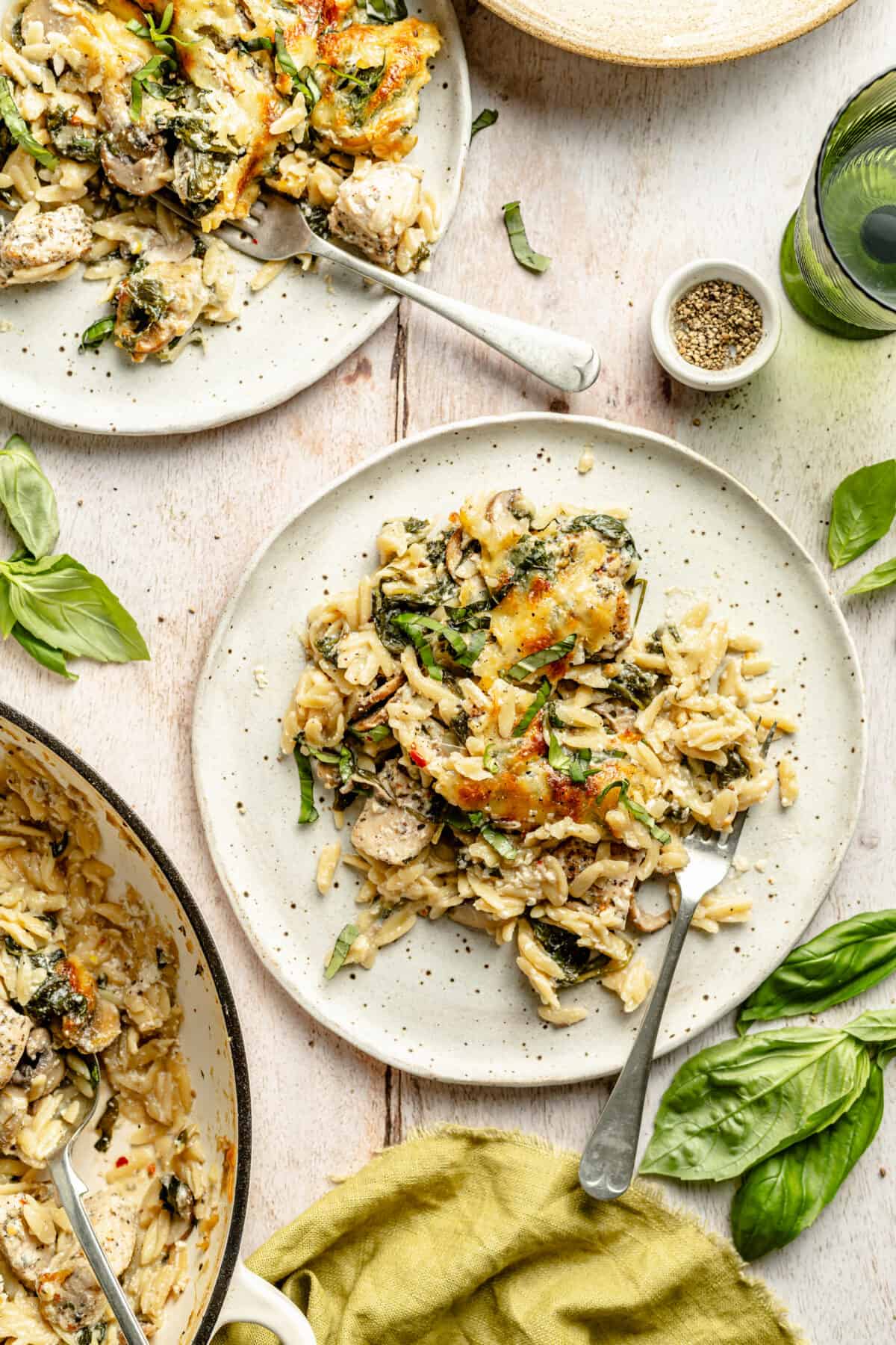 Creamy Ricotta Chicken and Orzo Skillet plated on two plates with skillet peeking in.
