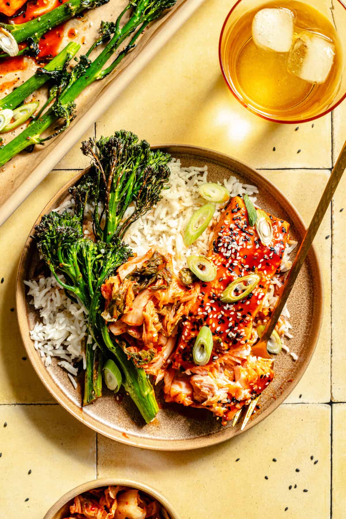 Overhead shot of Gochujang Glazed Salmon on a plate with broccolini. Fork is placed into salmon.
