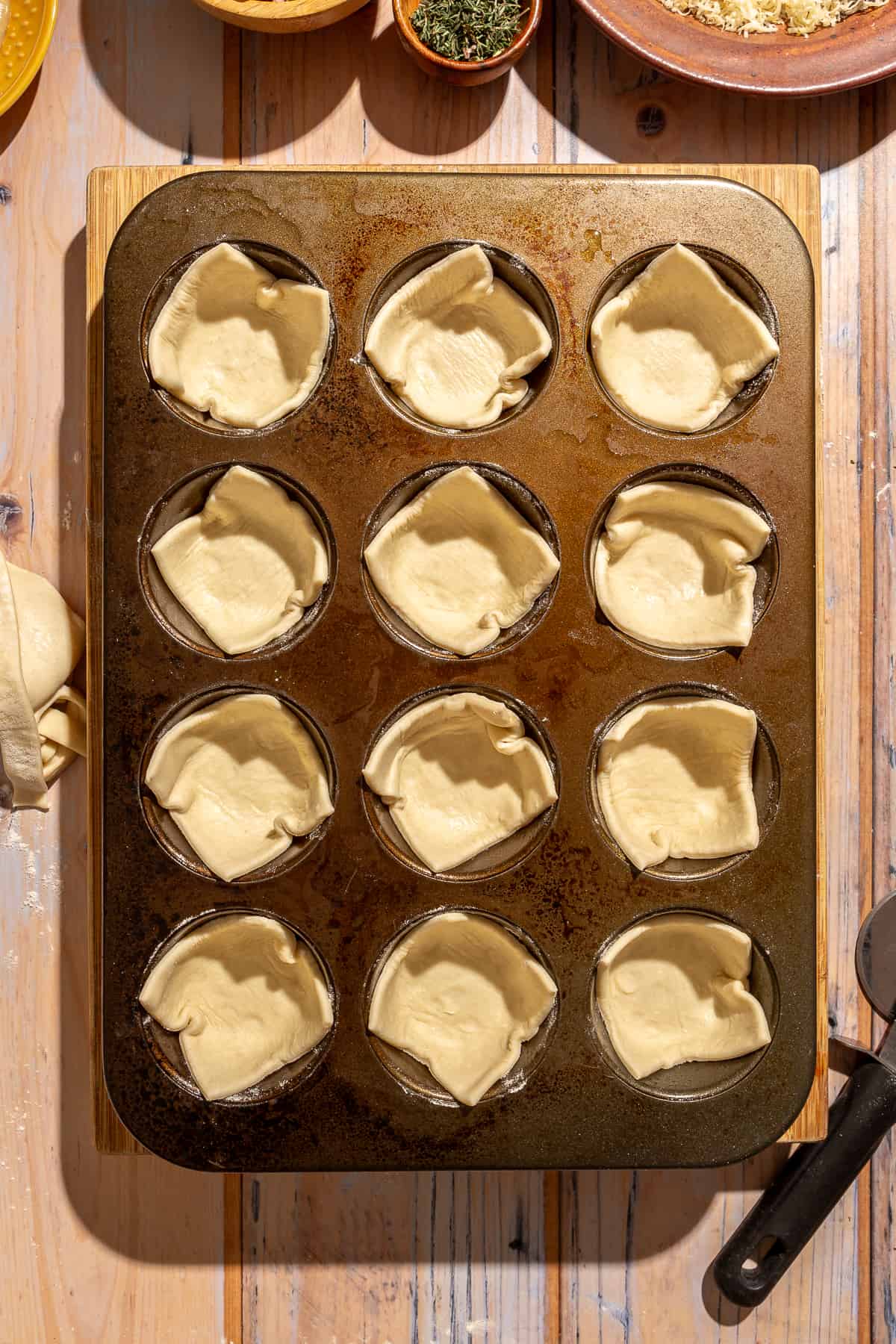 Cut pastry placed into each muffin pan opening.