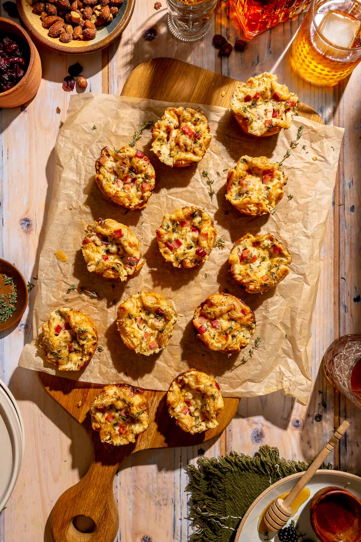 Mini Croque Monsieur Bites on wooden cutting board. Other appetizers and cocktails peeking in from top corners.