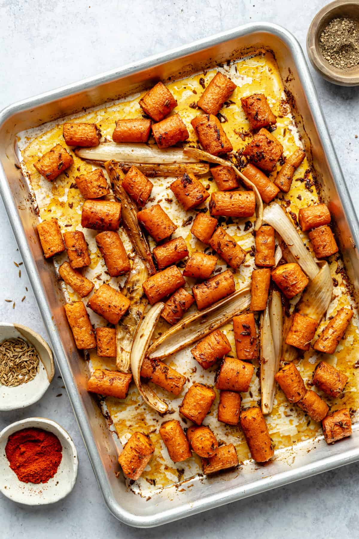 Roasted carrots and shallot on silver sheet pan.