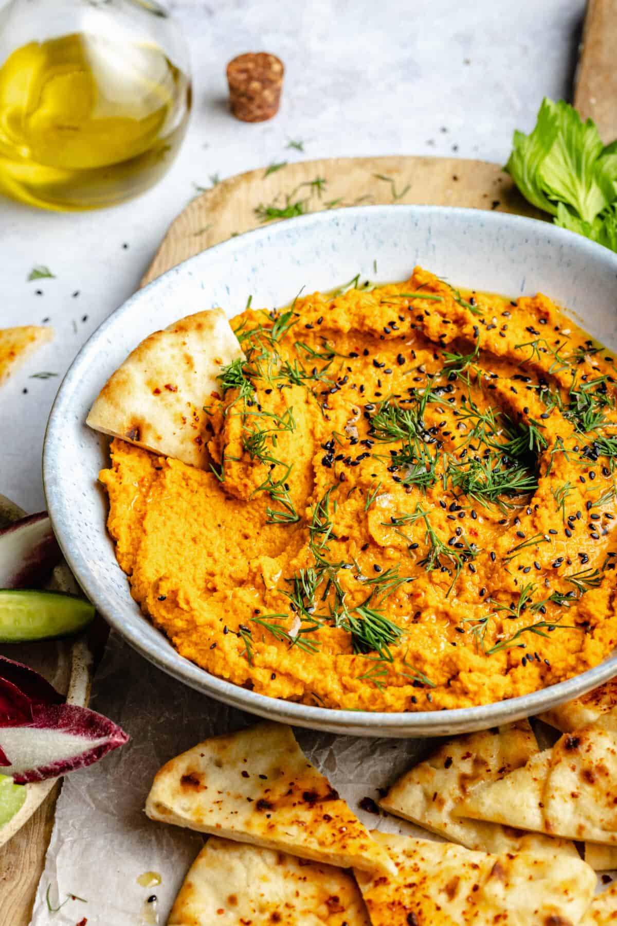 Harissa Carrot Dip in bowl with piece of pita in it.