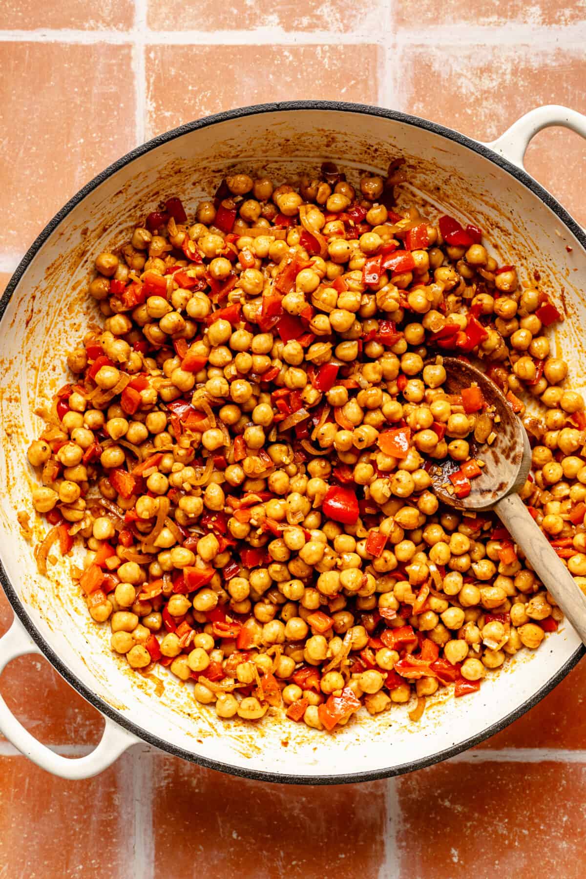 Chickpeas and other ingredients in a white skillet.