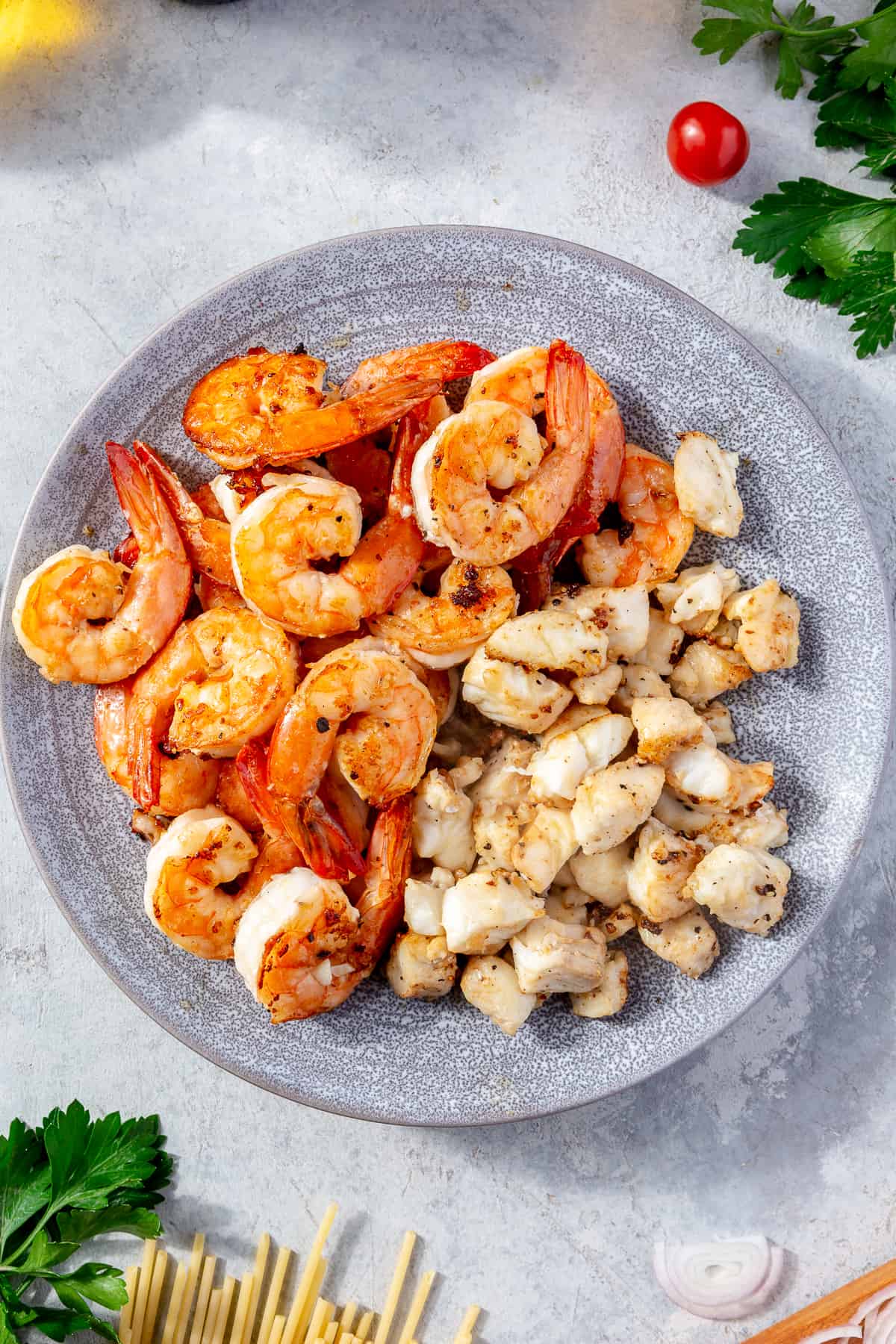 Cooked shrimp and halibut  on a light blue plate.