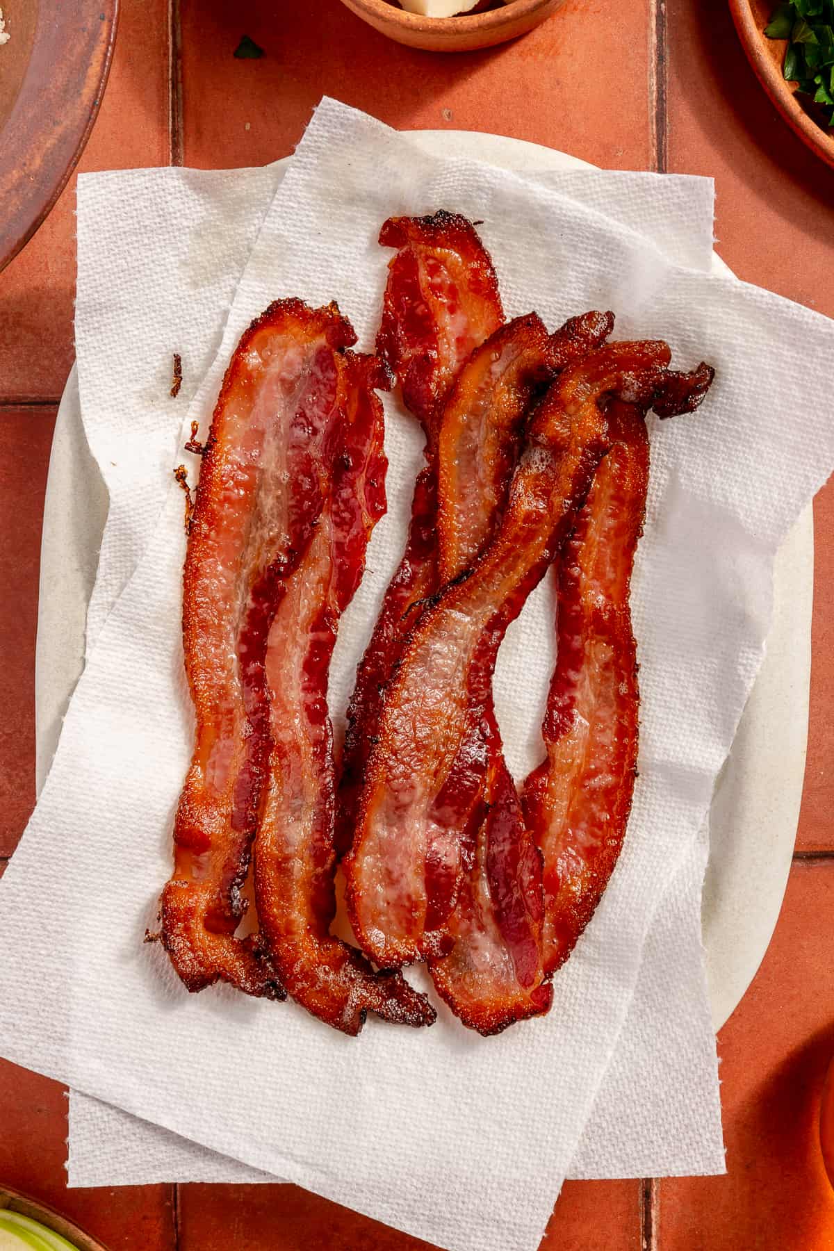 Crisped bacon on paper towel lined plate.