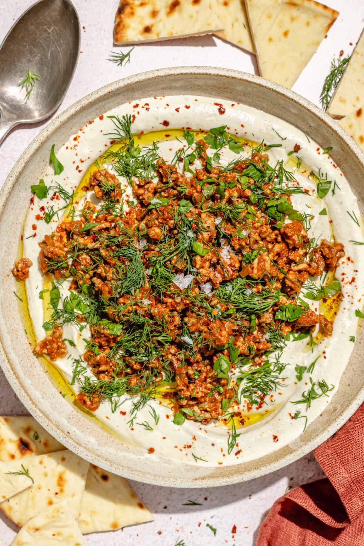 Spicy Lamb and Eggplant Labneh in a low bowl. Pita scattered around.