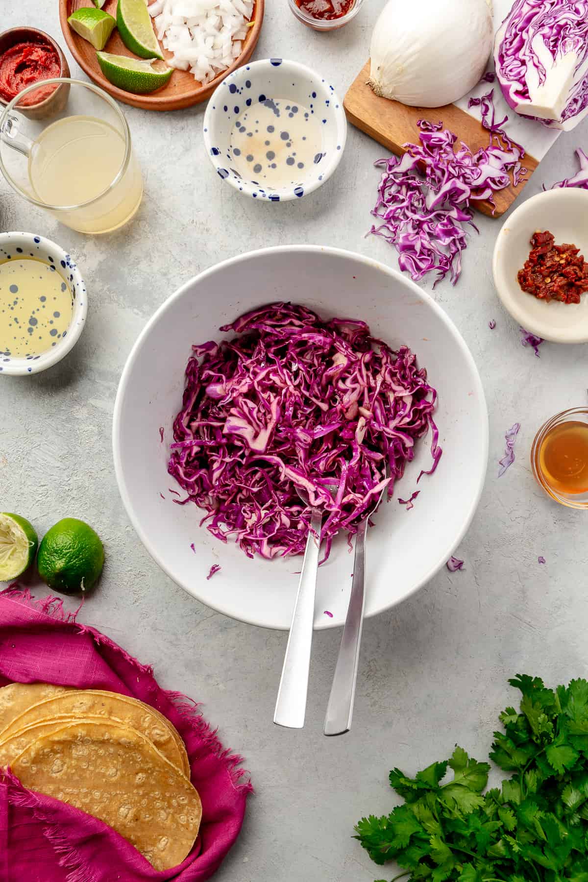 Slaw in a large white bowl with ingredients scattered around.