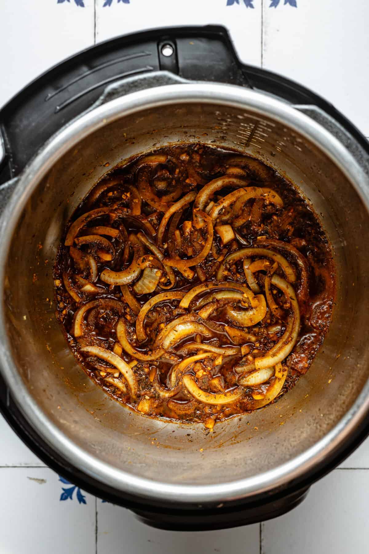 Onions, garlic, and other seasonings in Instant Pot.
