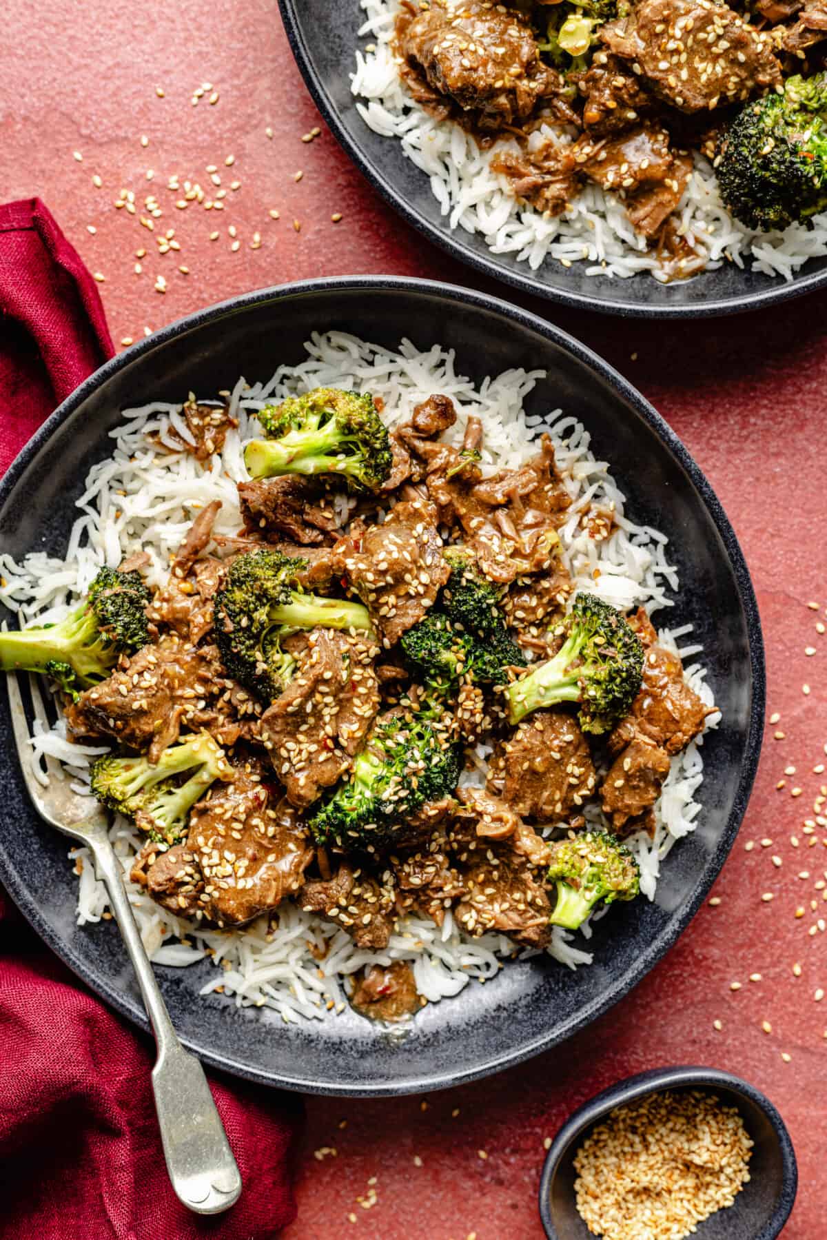 Slow Cooker Beef and Broccoli in bowls on red background.