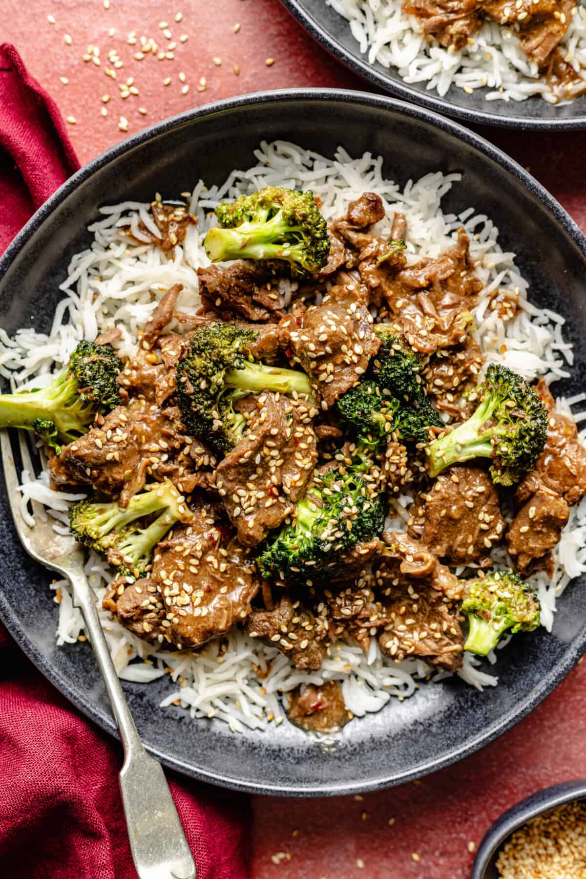 Slow Cooker Beef and Broccoli in bowls on red background.