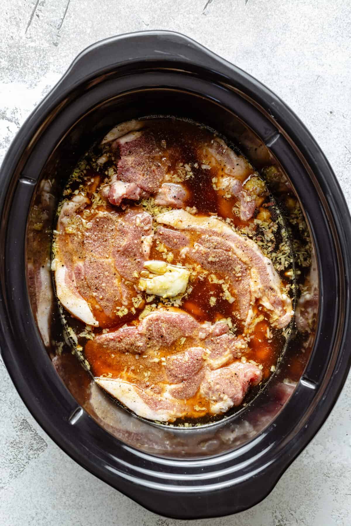 Raw pork and other ingredients in slow cooker.