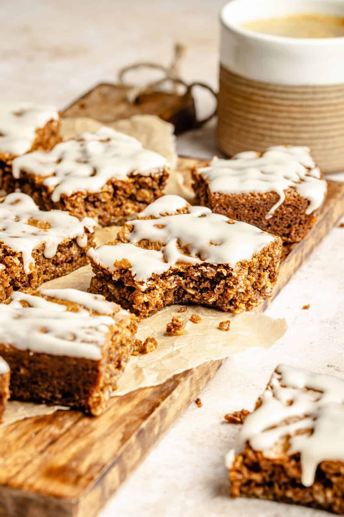 Iced Oatmeal Cookie Bars on board. Bite taken out of a bar.