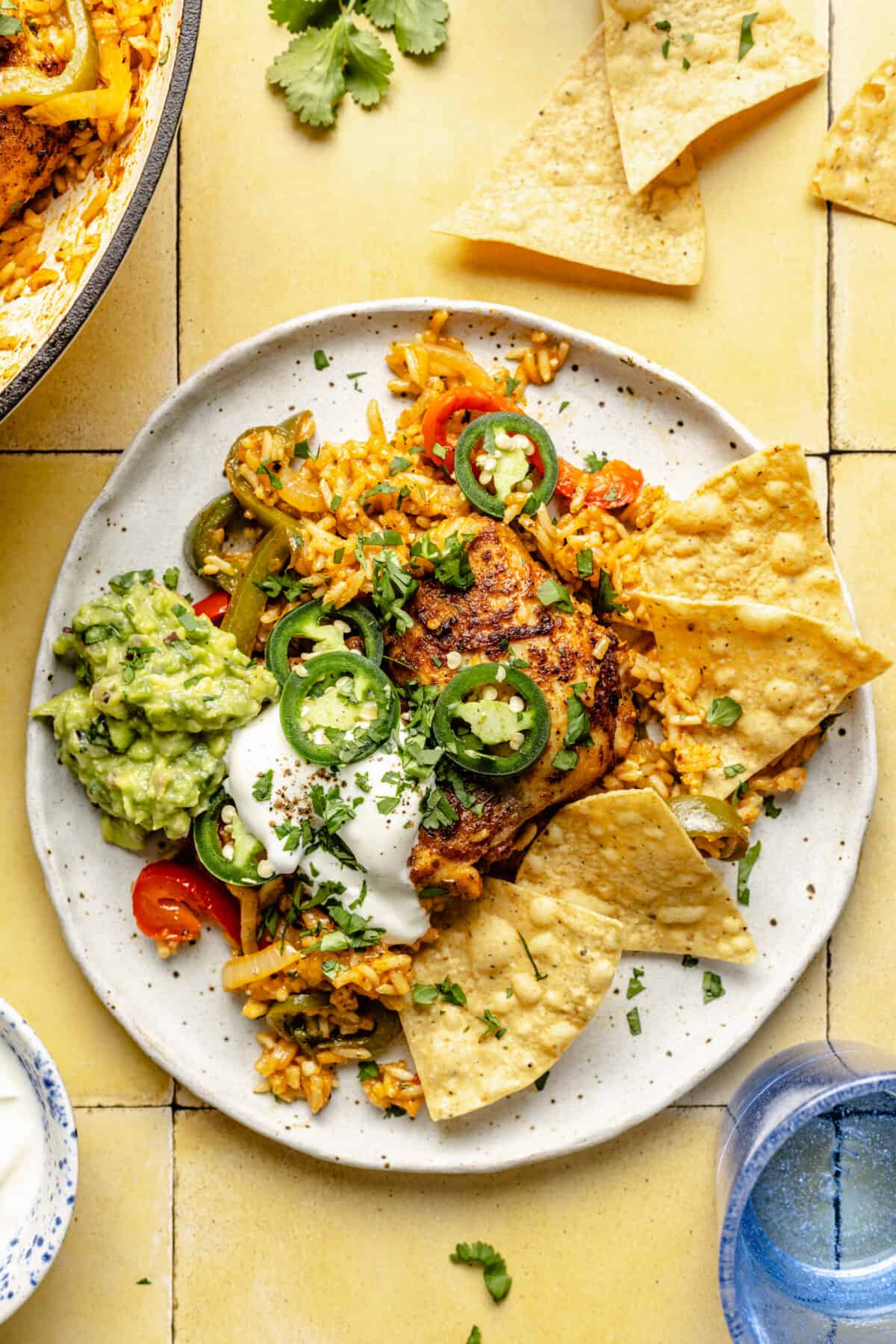 Chicken and Rice Taco Skillet plated with sour cream, guacamole, and chips.
