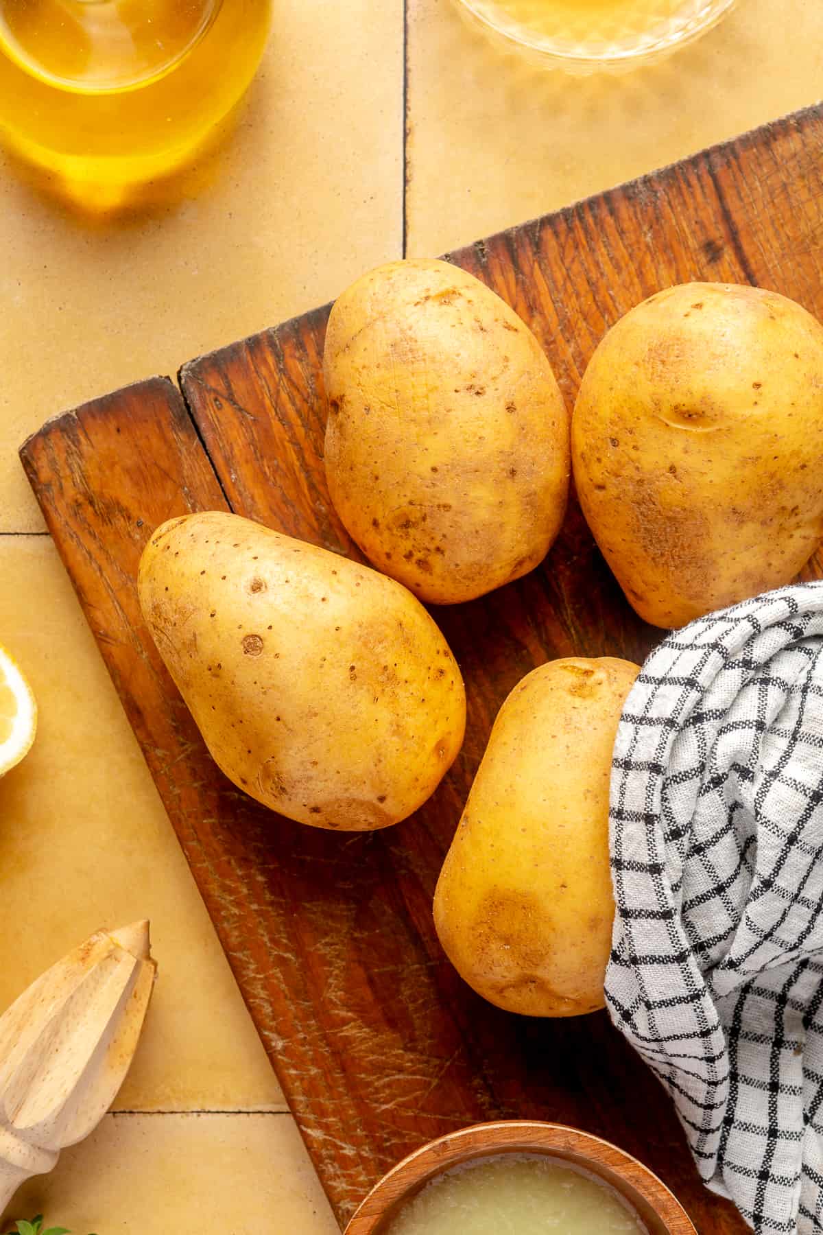 Whole potatoes on wooden board with kitchen towel. 