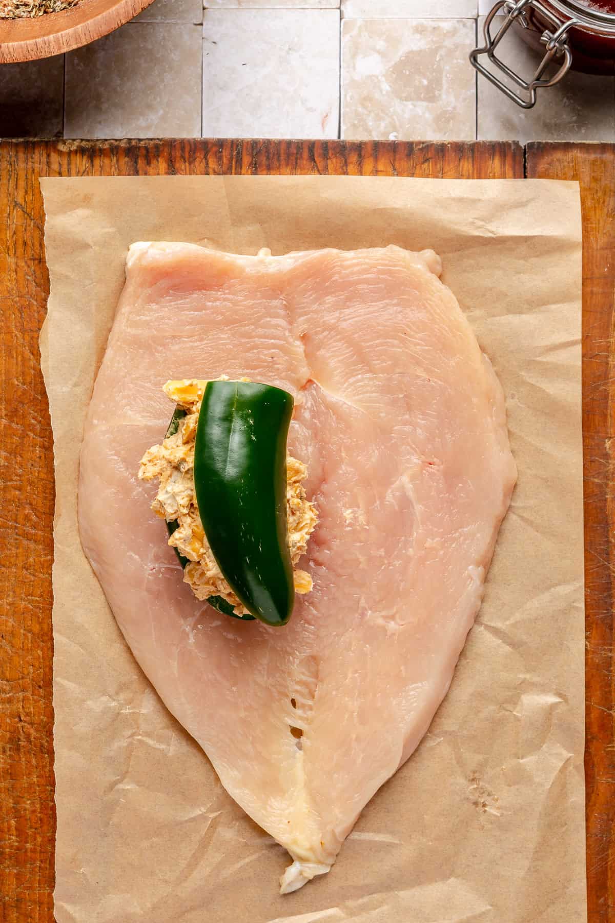 Chicken breast on cutting board stuffed with jalepeno and cream cheese filling.