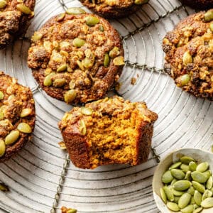 a close-up of pumpkin muffins topped with a pepita streusel on a round wire rack