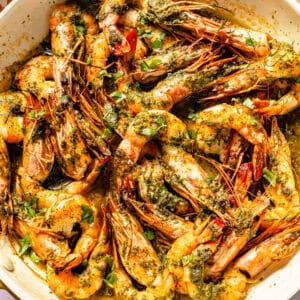 a white bowl with cooked shrimp tossed in parsley