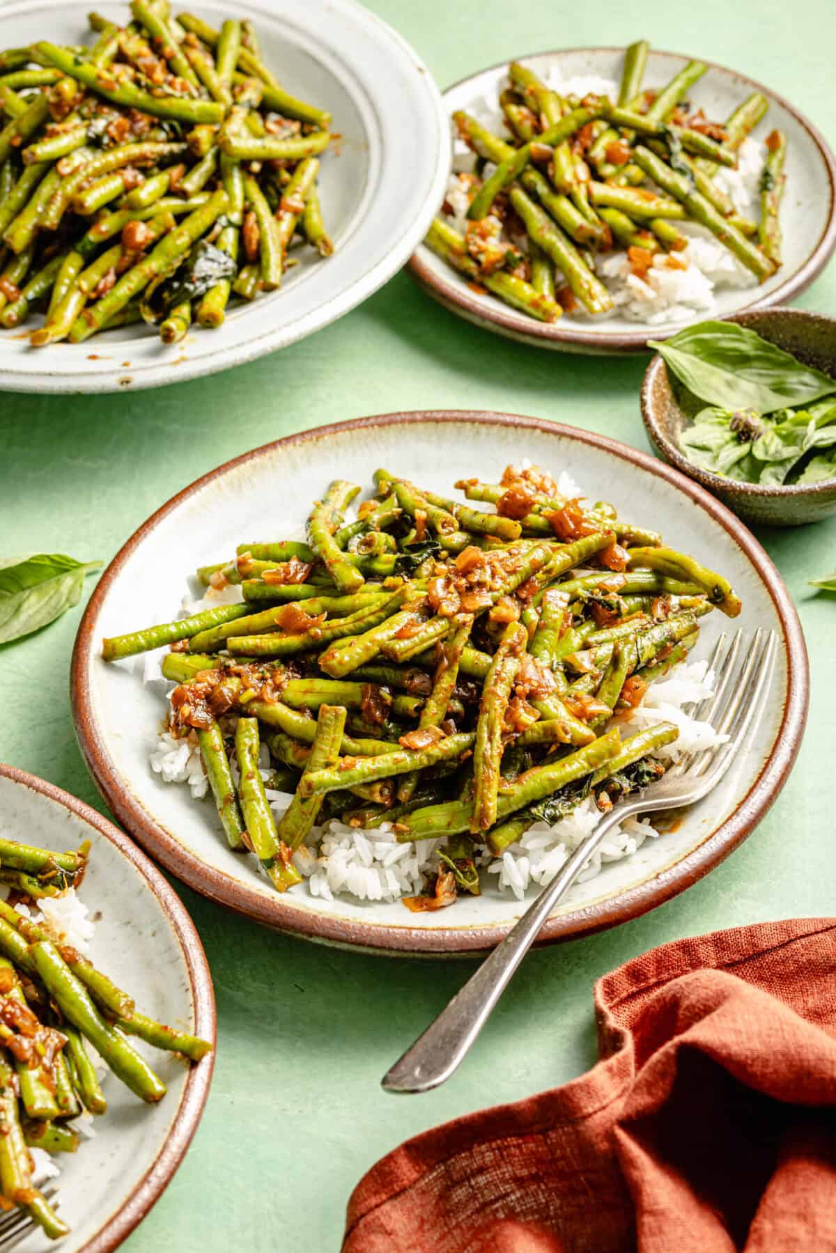 three white plates green beans on a bed of white rice and a green background