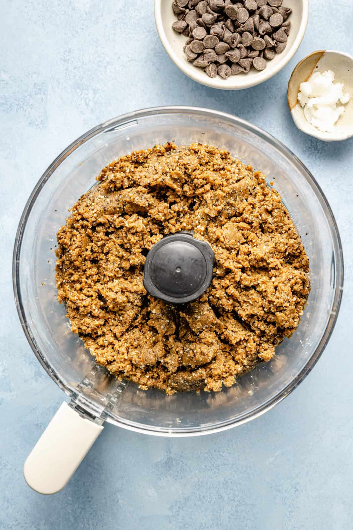 a food processor with a nut batter on a light blue background