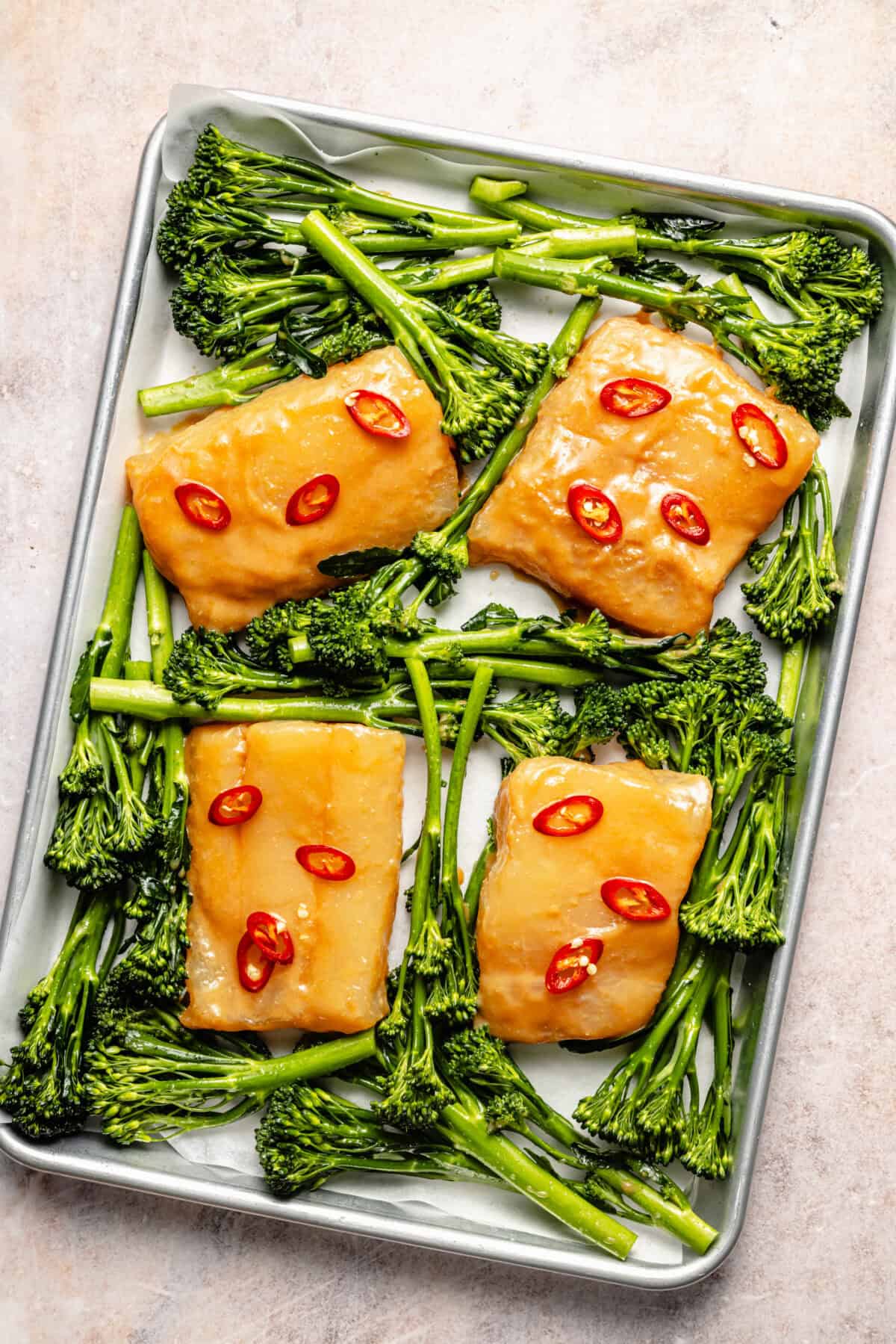 an aluminum sheet tray with miso-marinated cod, spicy peppers, and broccolini