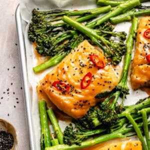 an up-close shot of miso marinated cod with spicy peppers, sesame seeds, and broccolini on an aluminum sheet tray
