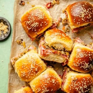 an up-close shot of individual muffuletta sliders sprinkled with sesame seeds