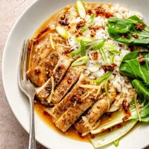 an up-close of seared chicken thighs with white rice, bok choy, and sliced scallions