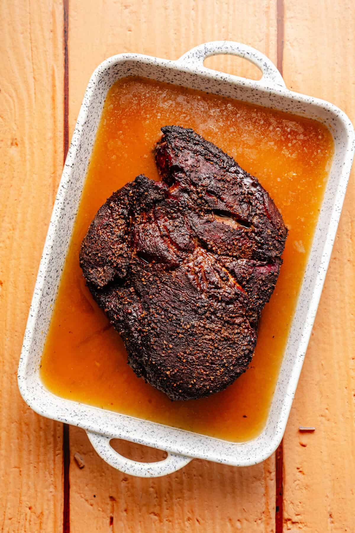 chuck roast in braising liquid in a white baking dish