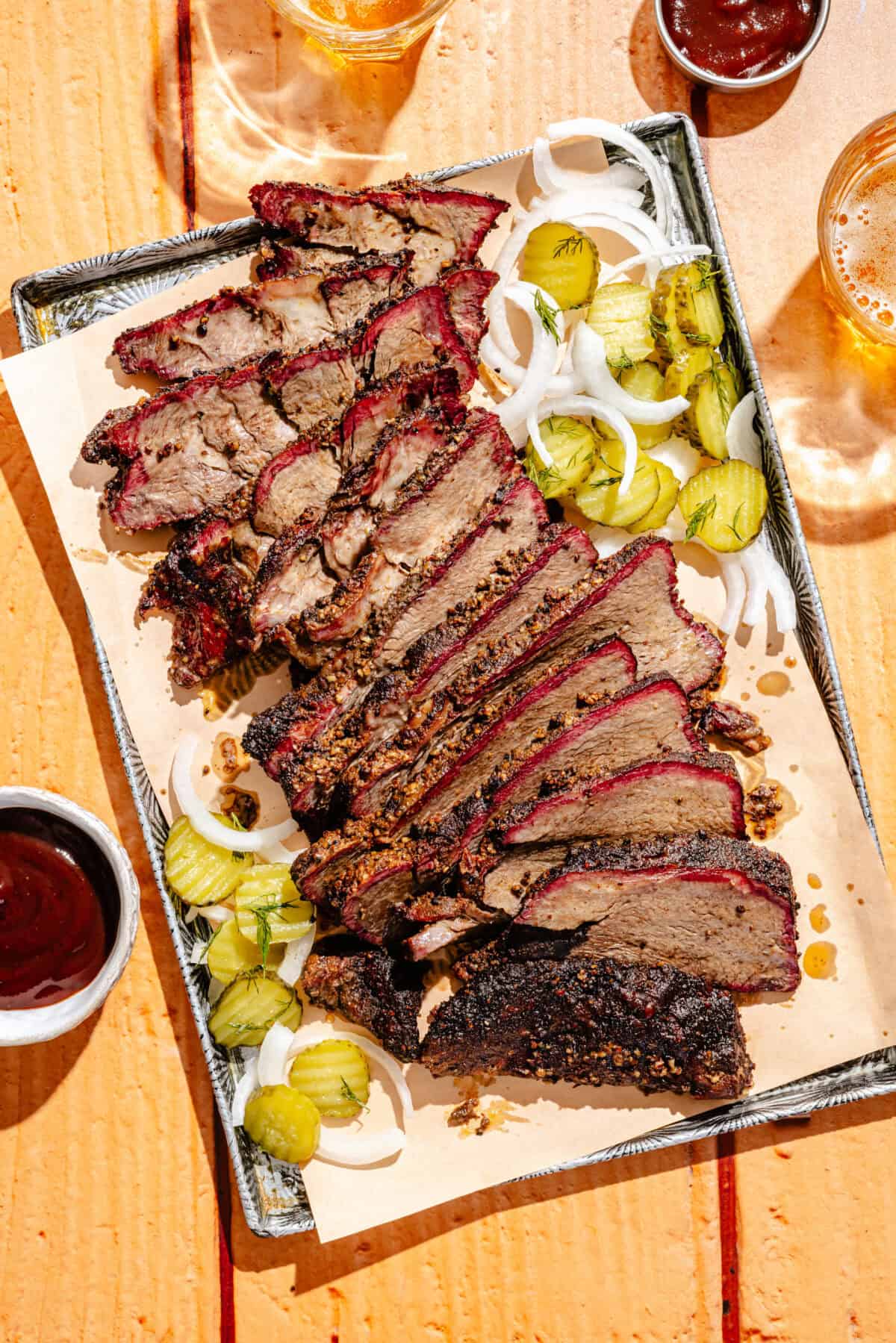 a sheet tray with smoked chuck roast with pickles, onions, and barbecue sauce