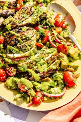 an up-close photo of green goddess marinated grilled chicken thighs with summer salad