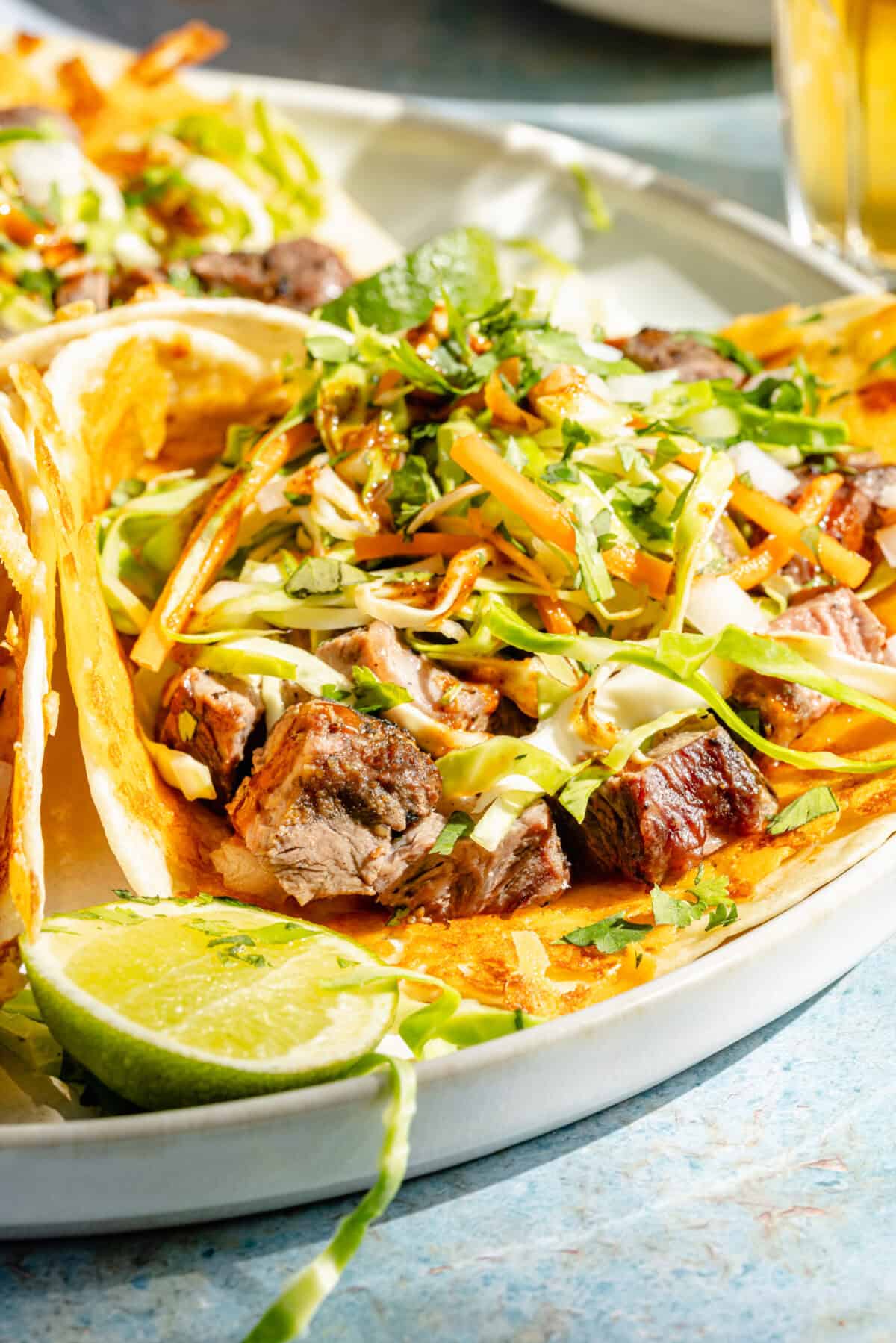 a close-up of grilled ribeye tacos with cabbage slaw and cheese-crusted tortillas