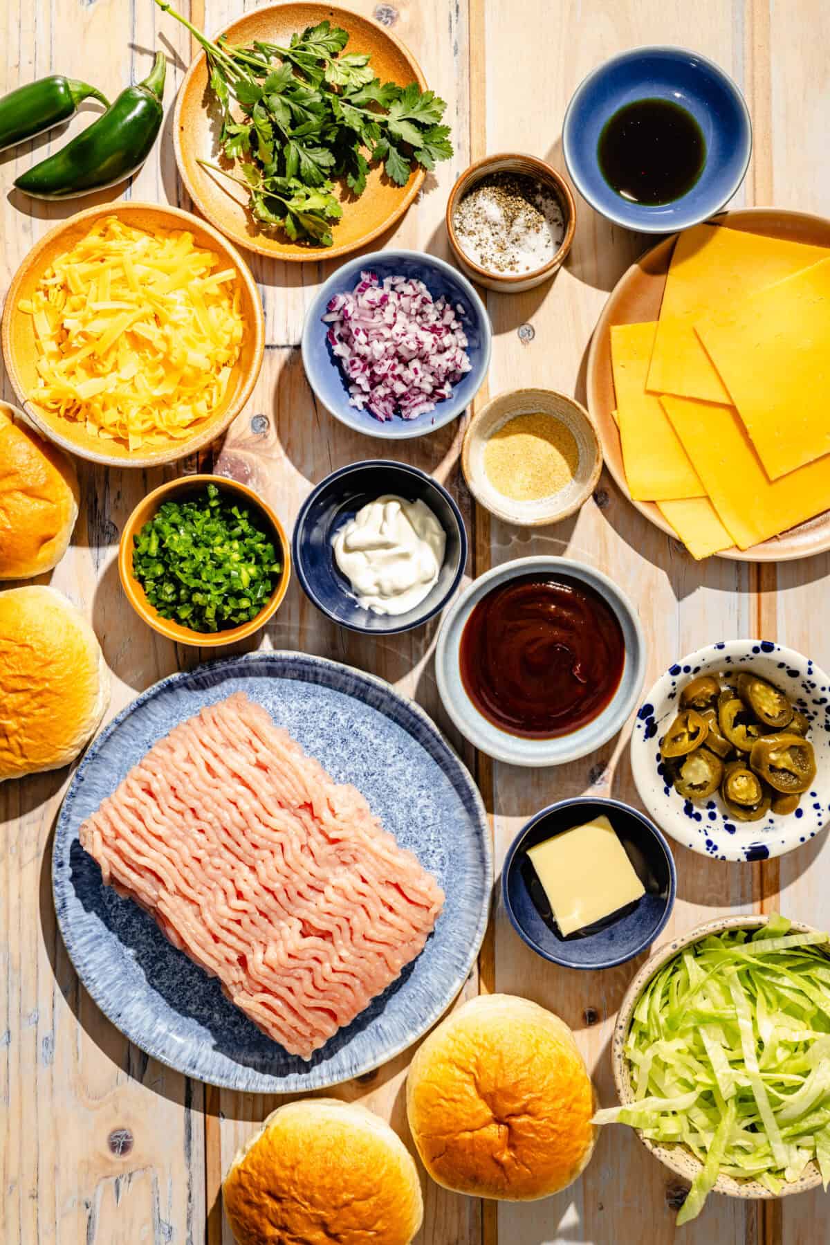 una capa plana de ingredientes necesarios para hacer hamburguesas de pavo con jalapeño y queso cheddar