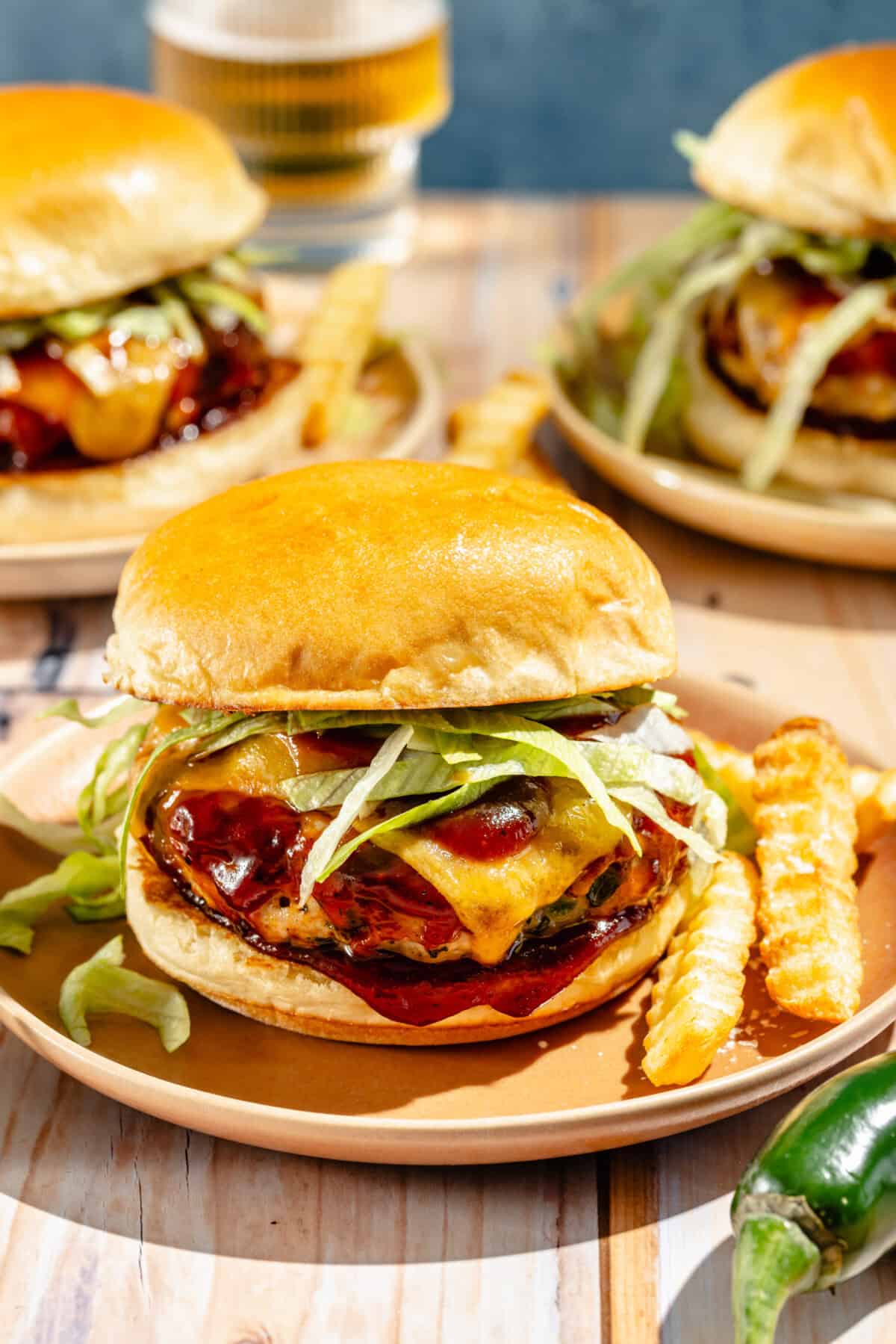 primer plano de hamburguesas de pavo con jalapeño y queso cheddar en un plato con papas fritas