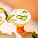 an overhead photo of a skinny margarita garnished with jalapeno peppers and lime