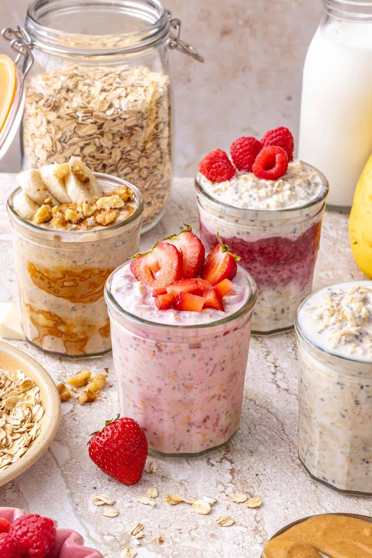 Easy Overnight Oats (3 Ways) displayed in jars with some ingredients behind them.