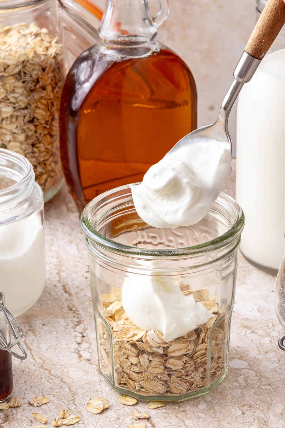 Oats in jar with yogurt going on top.