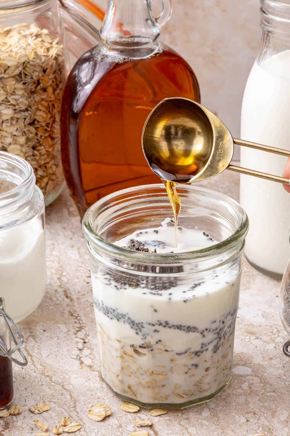 Overnight oats base in jar with syrup pouring into it.